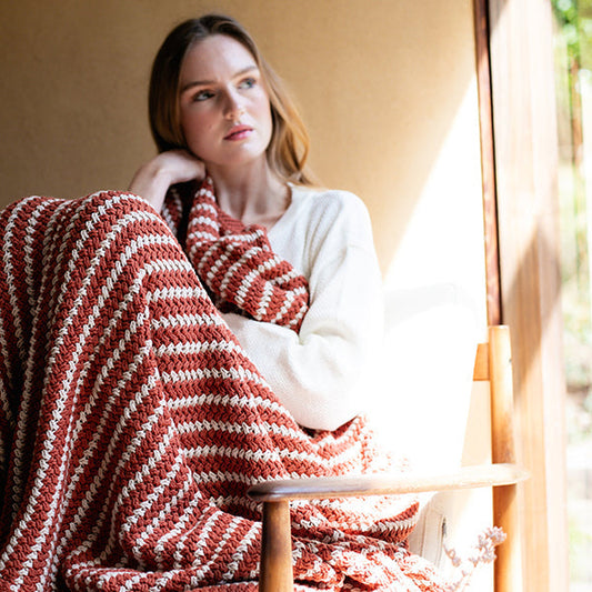 Rust and white striped knit throw blanket draped around shoulders