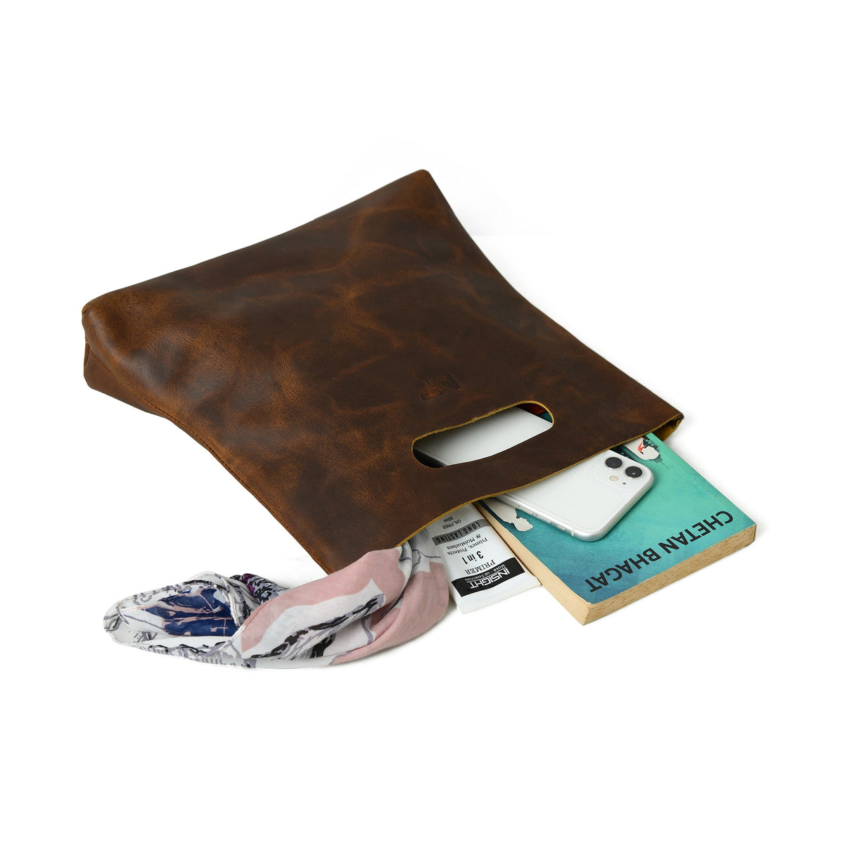 Brown leather handbag laid open, showing interior items and side cutout