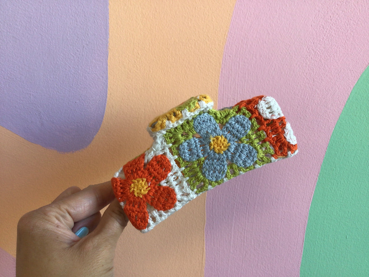 Crocheted hair claw with orange, blue, and green floral appliques