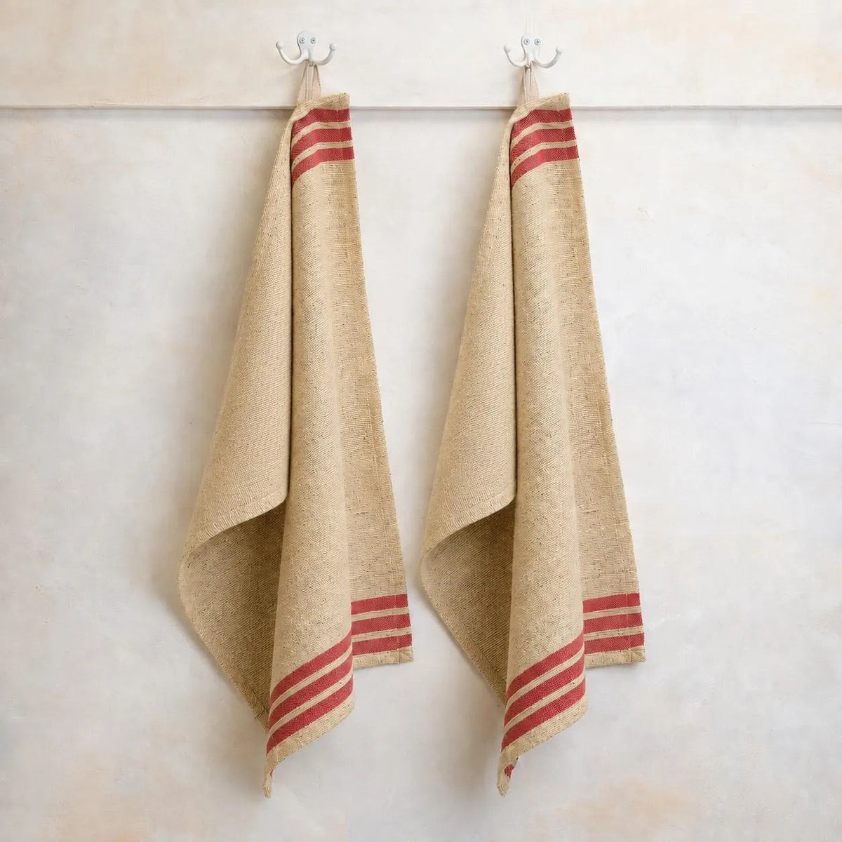 Handwoven cotton kitchen towels hanging on hooks with red striped border