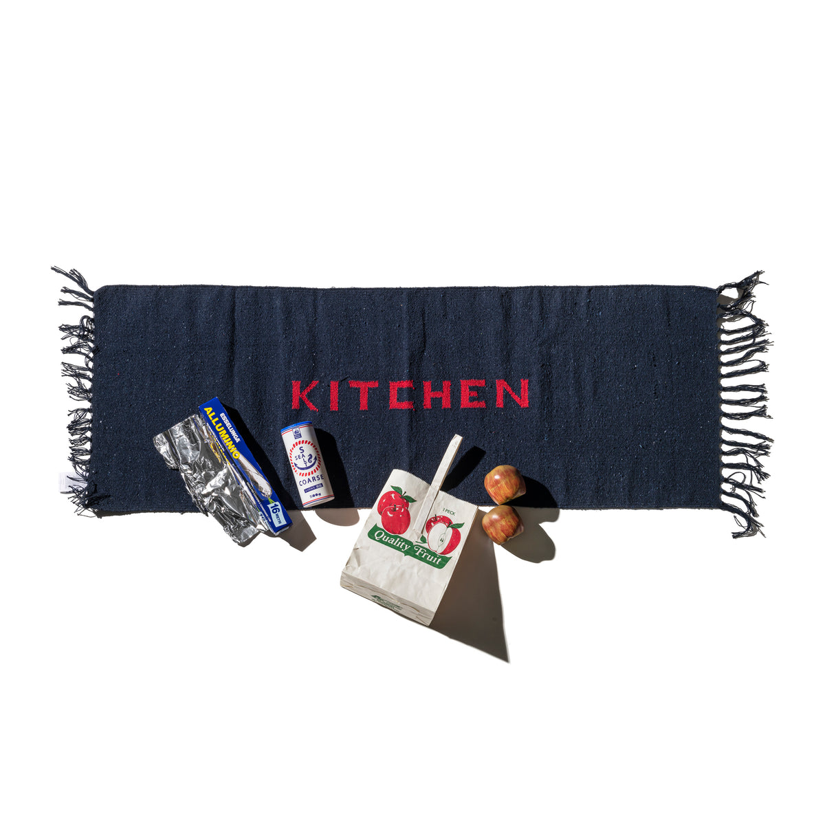 Navy blue kitchen mat with fringe edges and red 'KITCHEN' lettering
