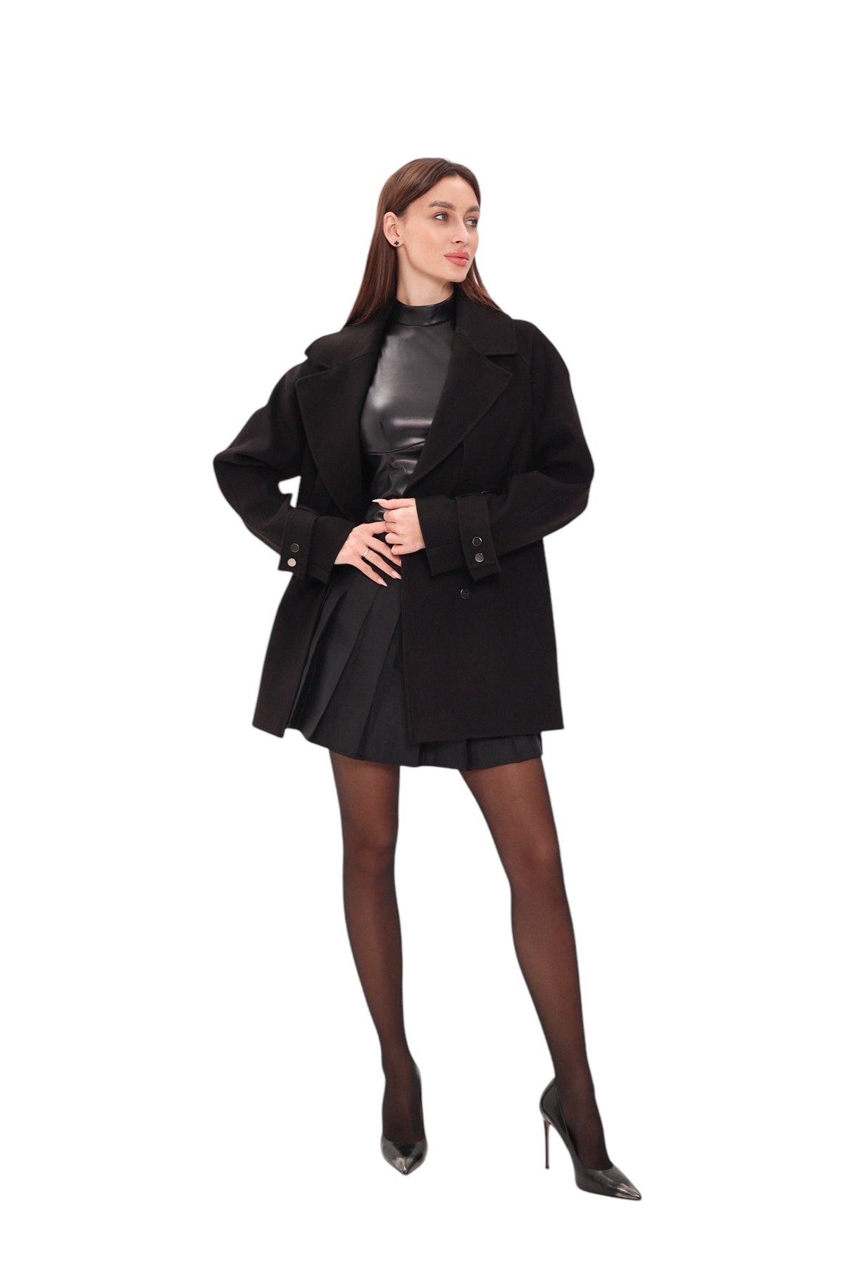 Black midi coat worn open over a pleated skirt, with wide lapels and belt