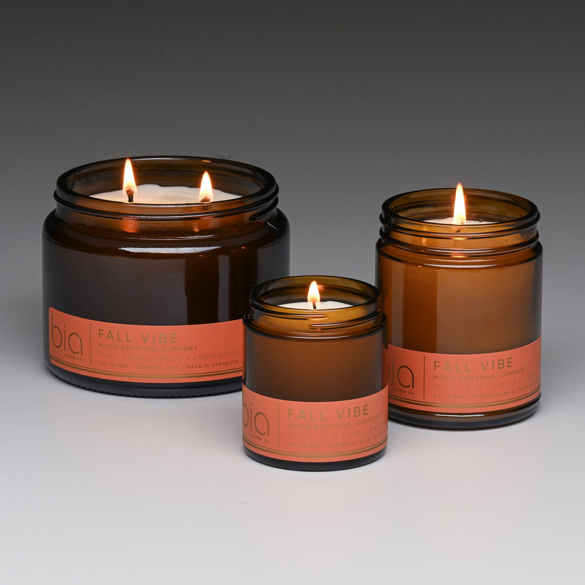 Set of amber soy candles in different sizes, each with lit wick and orange label