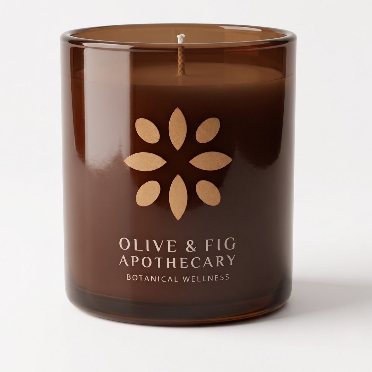 Unlit amber glass jar candle with floral emblem on smooth white surface