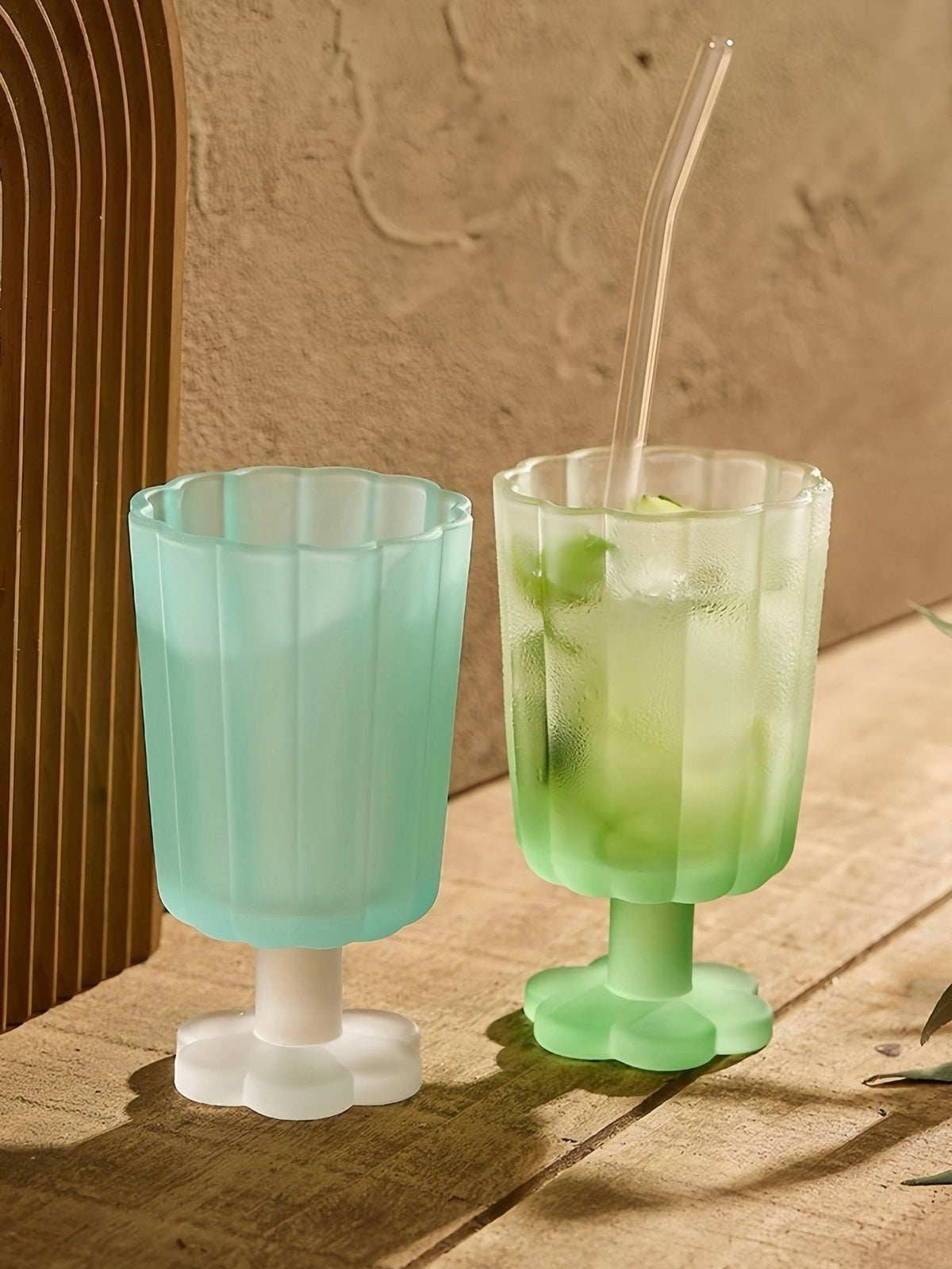 Hand-blown petal goblet glasses, teal and light green, with fluted cups and stem bases.