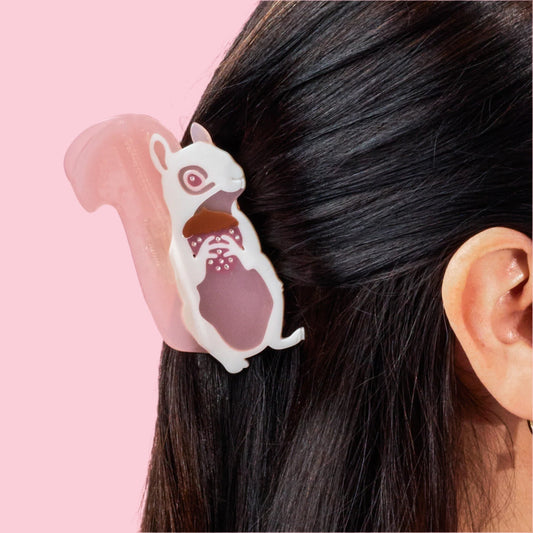 White and pink squirrel hair claw clipped on dark hair, side view