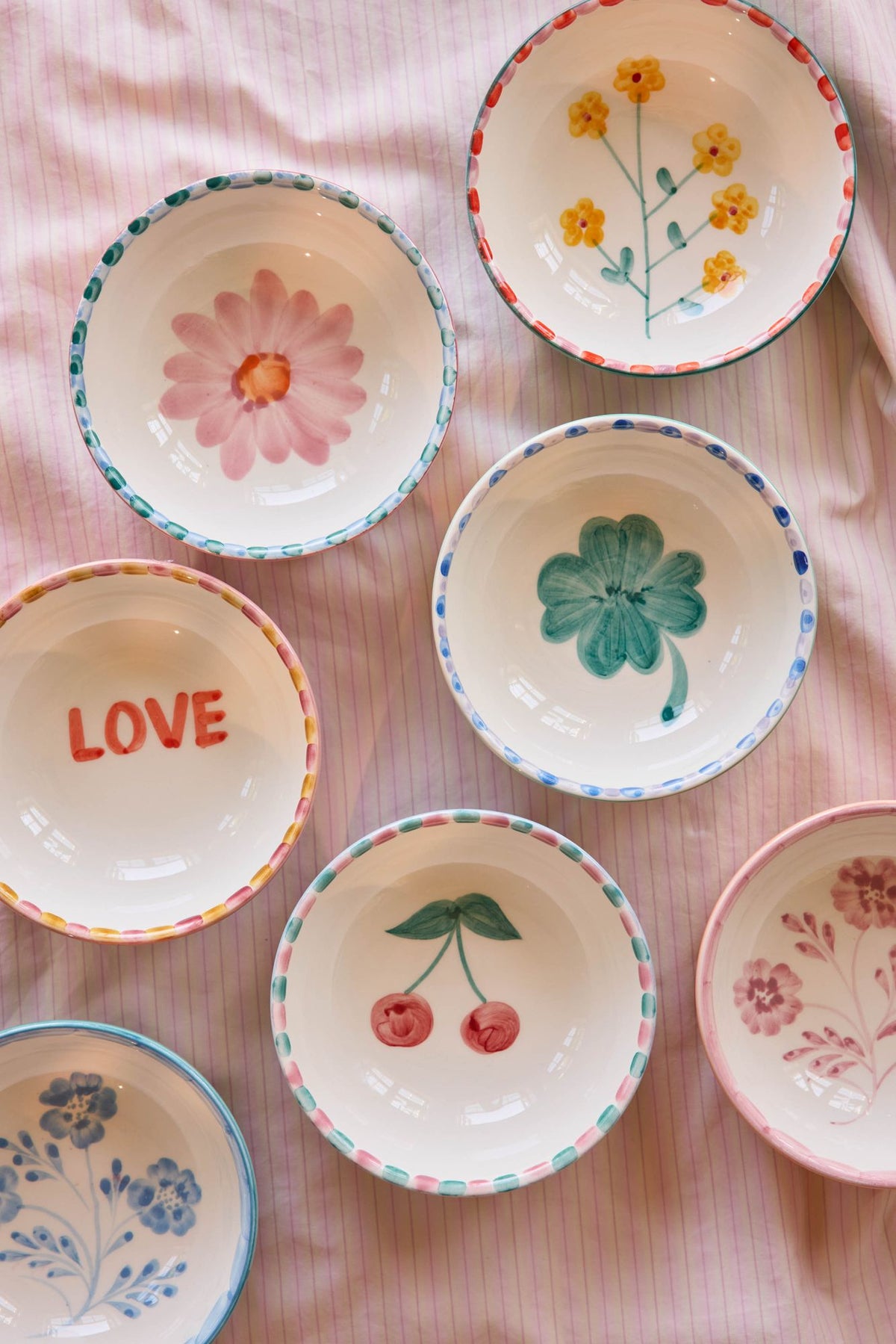 Assorted ceramic bowls with hand-painted florals, red dotted rims; one shows LOVE
