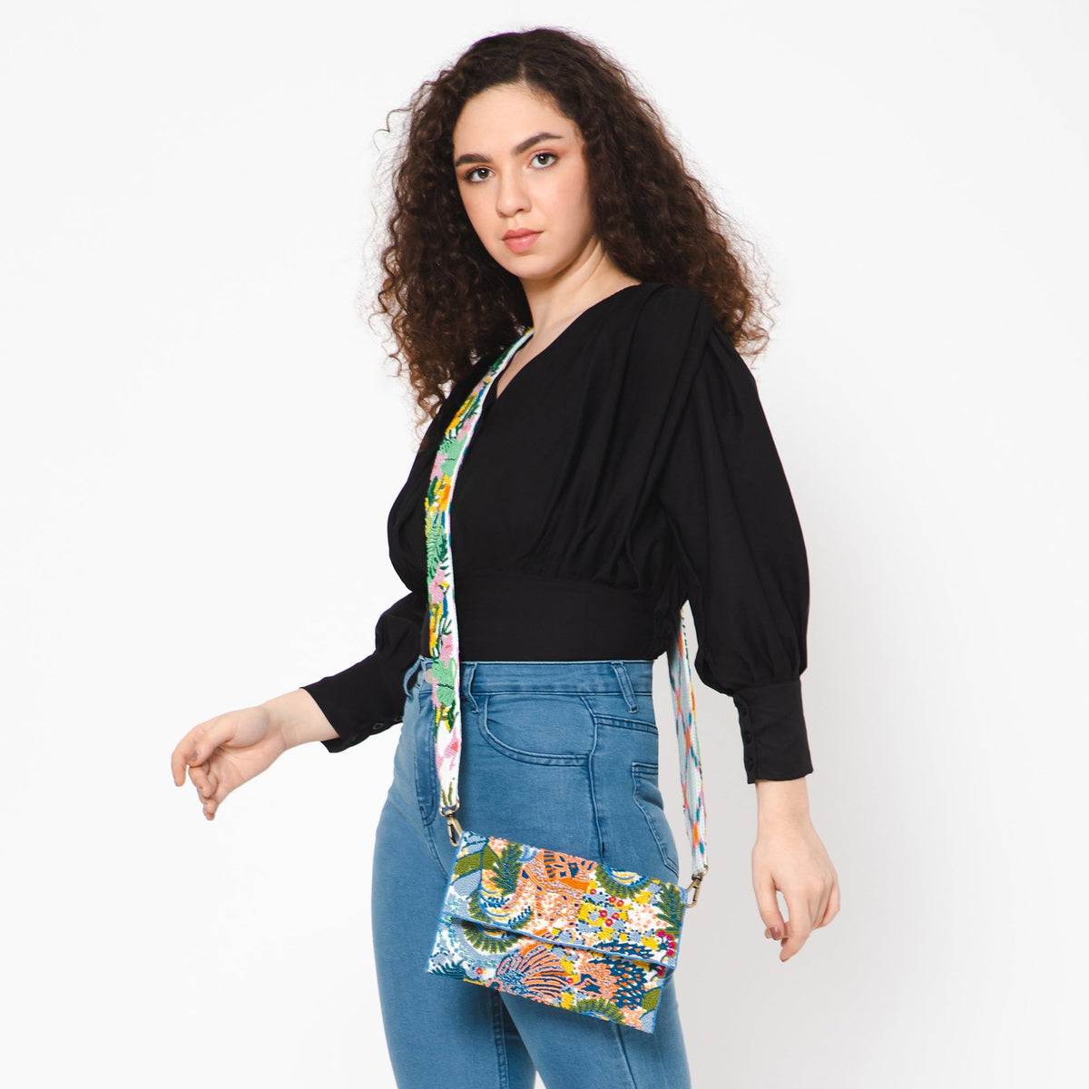 Floral embroidered crossbody strap holding a small multicolor pouch