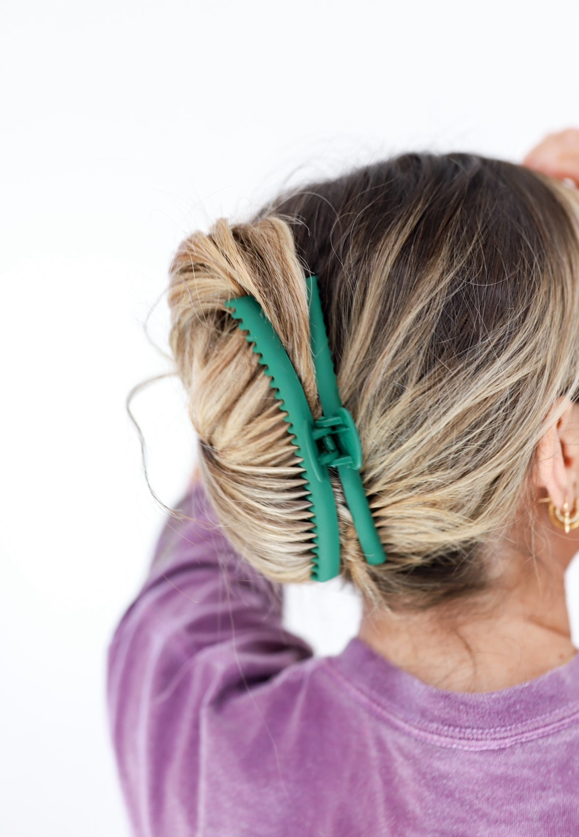 Close-up of mint green hair claw clip holding blonde hair