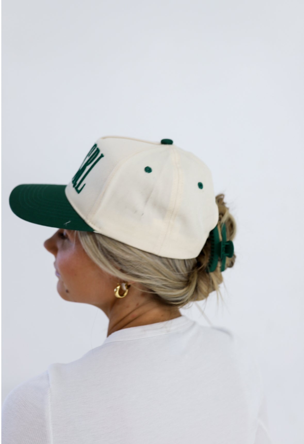 Matte mini hold-everything claw hair clip on blonde hair under a cream cap
