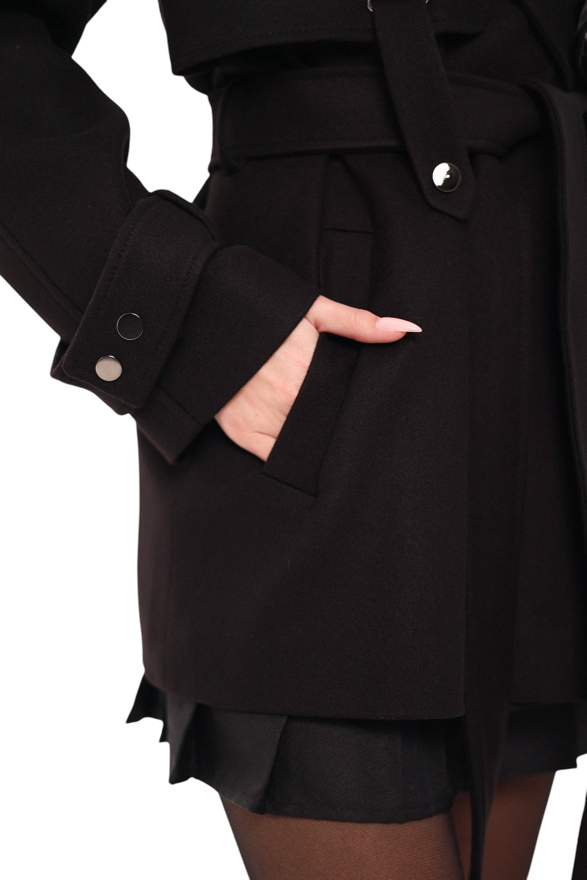 Close-up of the black coat's welt pocket, button-tab cuff, and waist belt.