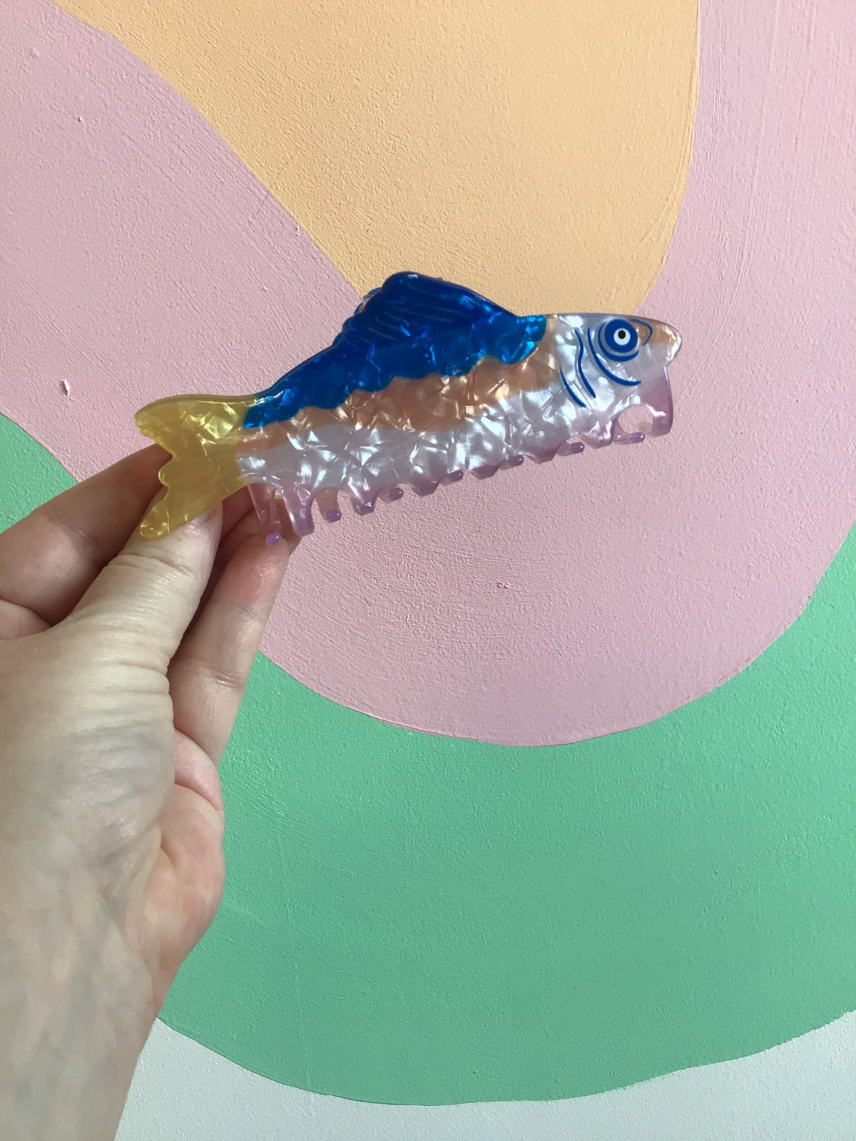 Clear and blue fish hair claw with translucent comb teeth and eye detail.