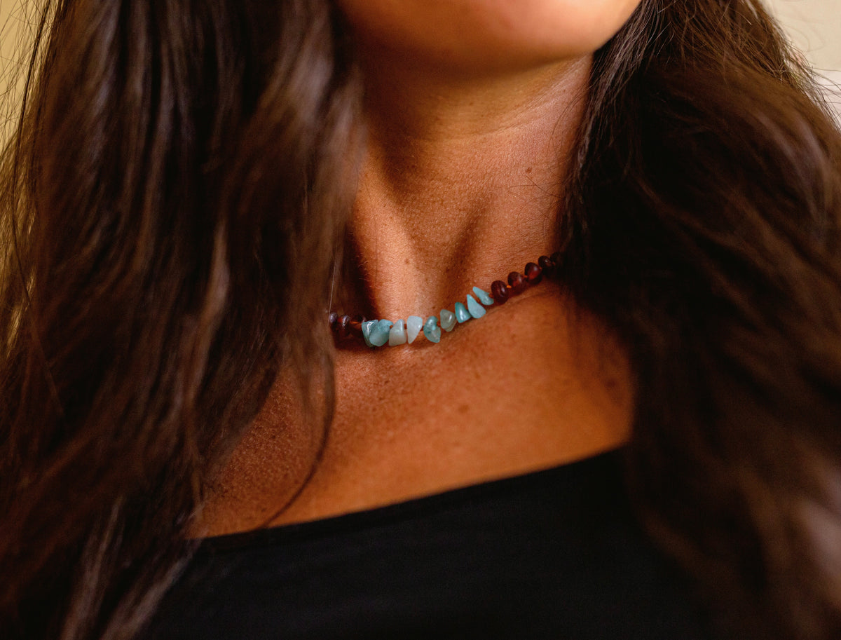 Amber-brown bead necklace with light blue stones on a wearer’s neckline