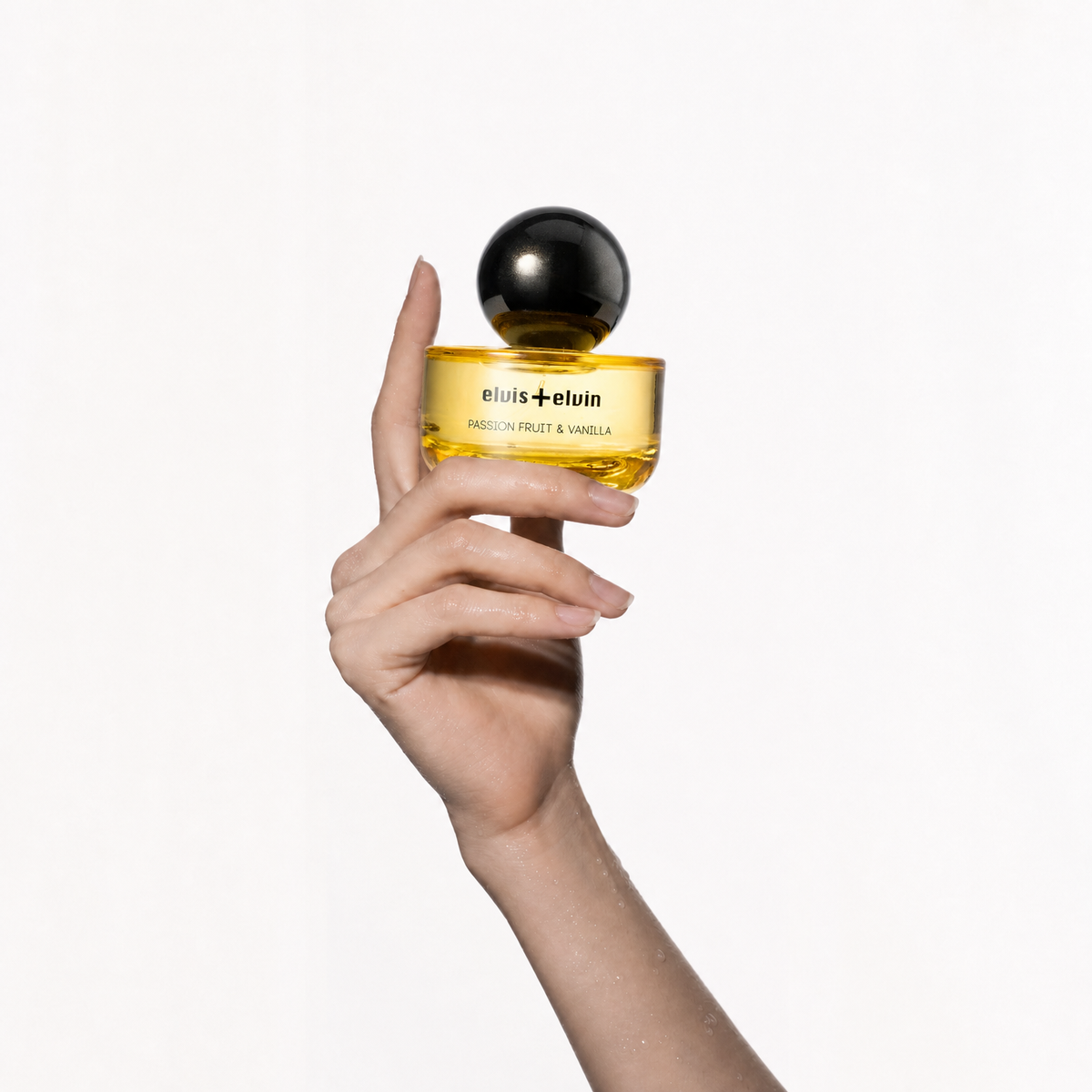 Passion fruit & vanilla parfum jar held in hands, black spherical cap, amber glass