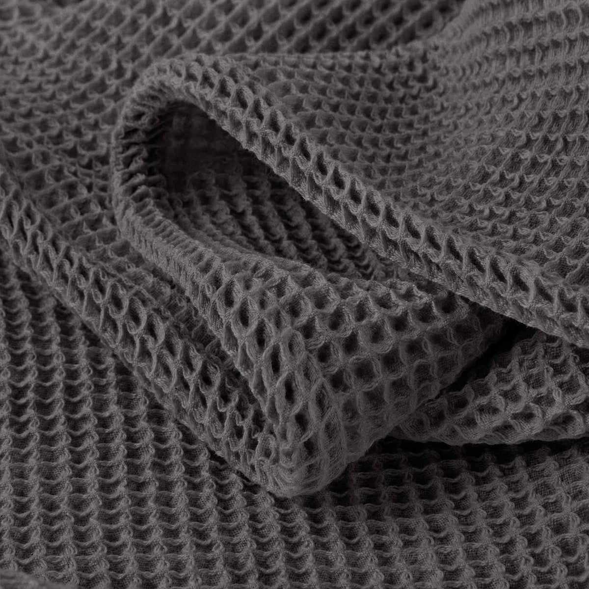 Dark grey waffle-knit blanket close-up of raised honeycomb texture.