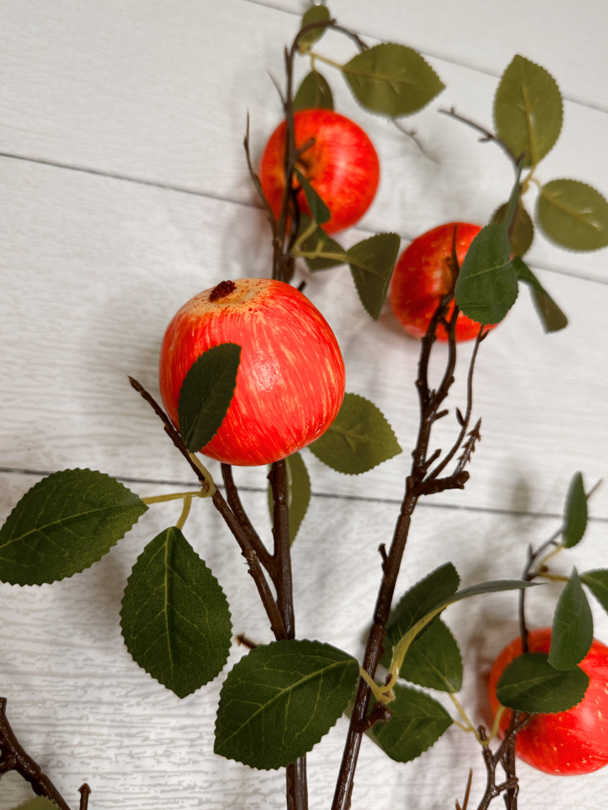 Artificial apple stem detail with red apples and green leaves on twig branches