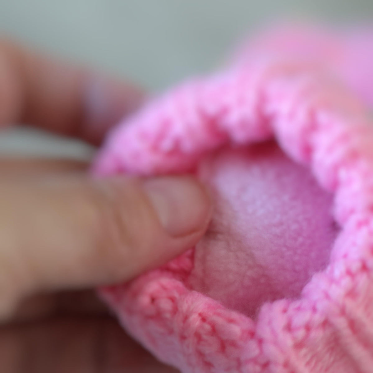 Pink knit mitten opened to show its soft fleece lining