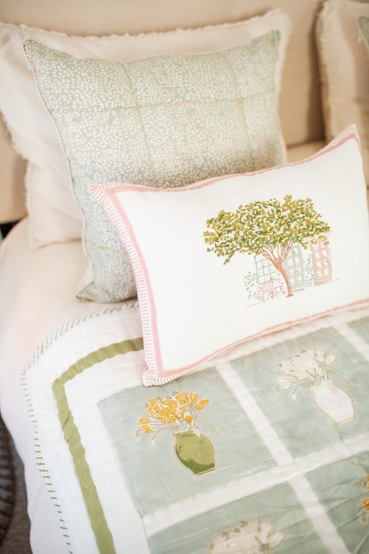 Block print cushion with tree-and-house front, pink trim, and blue patterned backing cushion behind
