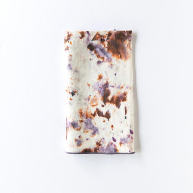 Marble-pattern napkin with white fabric, purple and brown speckled splatter, dark border.