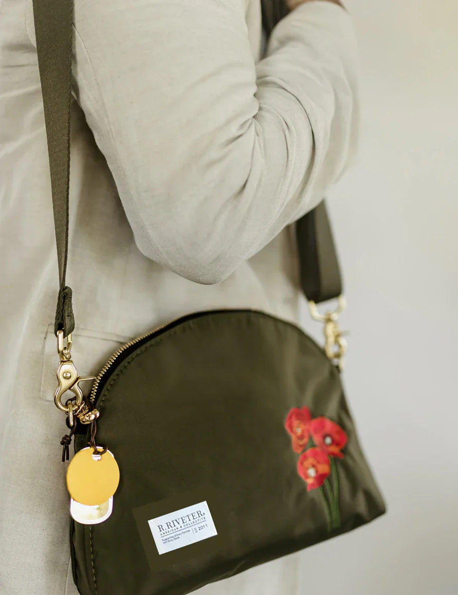 Olive nylon crossbody pouch with red floral patch, zipper, and yellow disc key charm