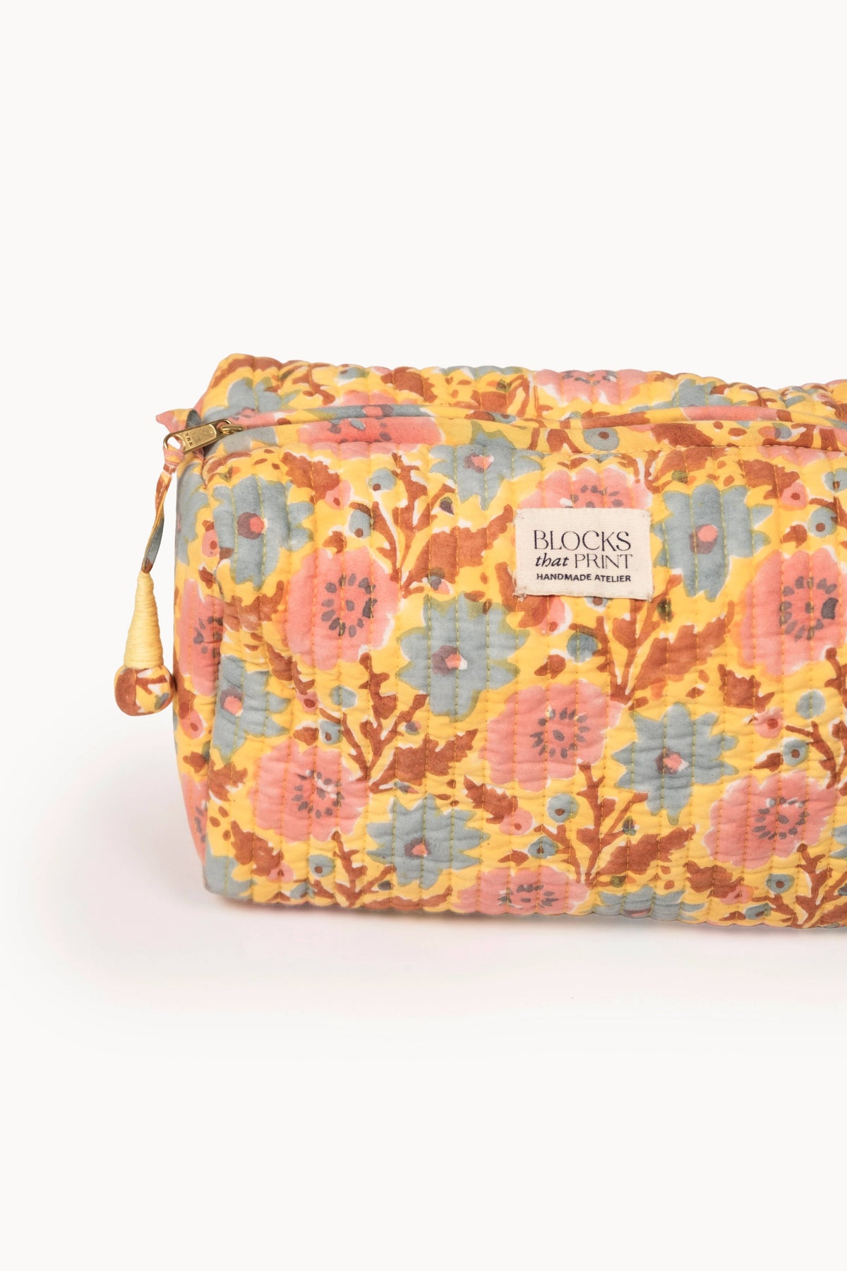 Quilted travel pouch close-up, orange floral block print with brand label