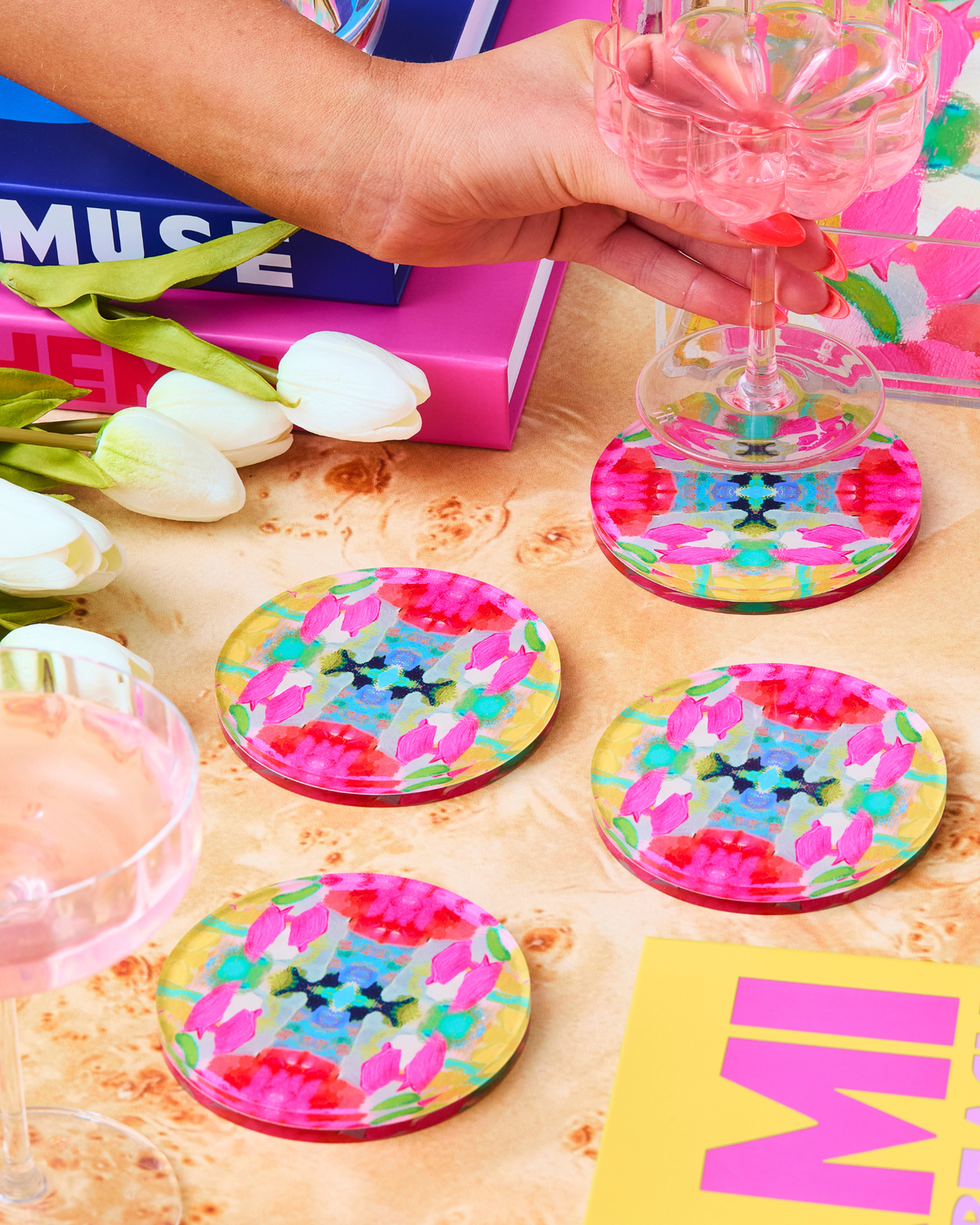 Set of round acrylic drink coasters with pink, green, and blue floral confetti pattern
