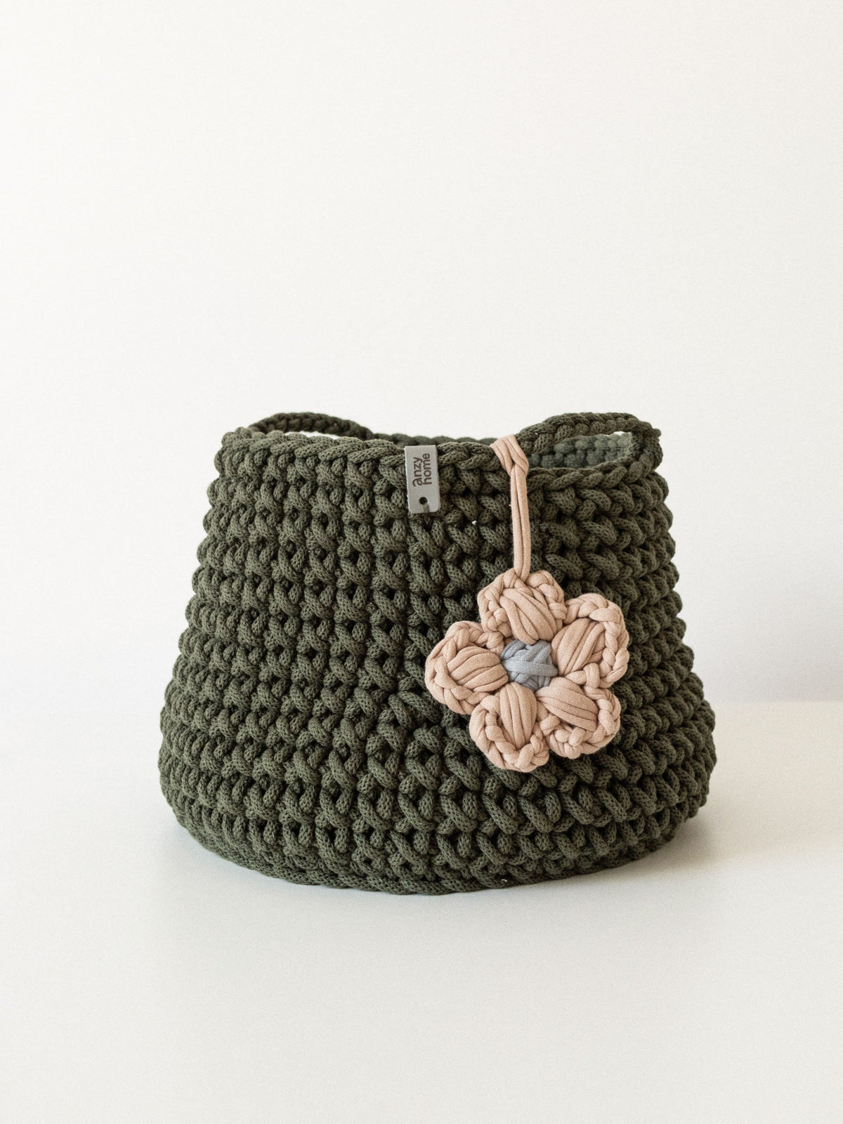 Olive green crochet storage basket with pink flower applique and braided handles