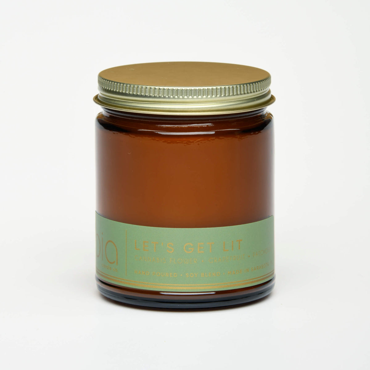 Amber jar candle with metal lid and green label, unlit
