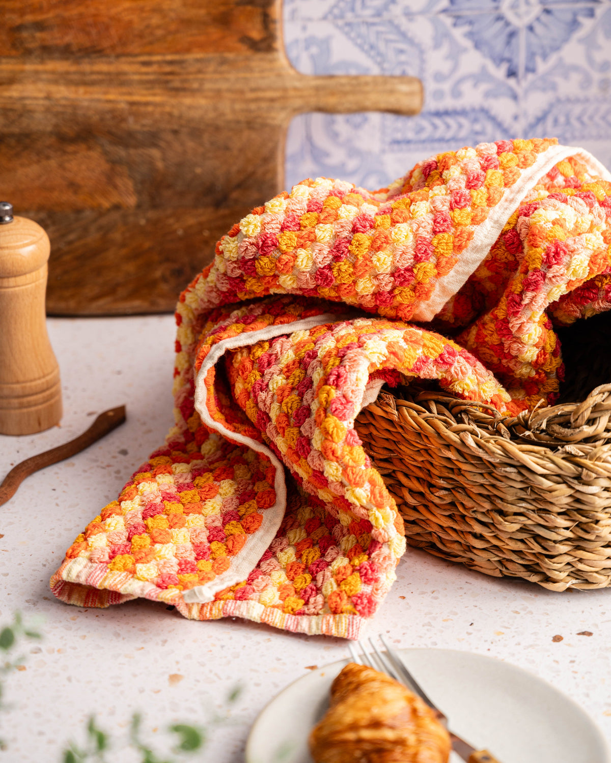 Folded checkered hand towel in coral and orange tones with cream, no tassels.