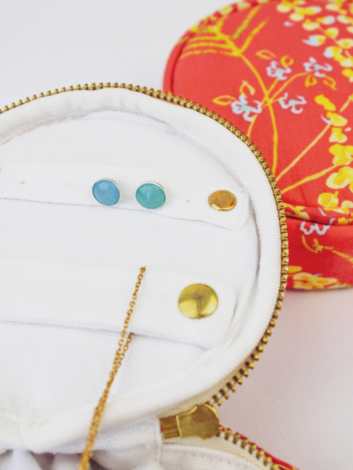 White-lined jewelry pouch interior with gold zipper and blue and gold earring holder loops
