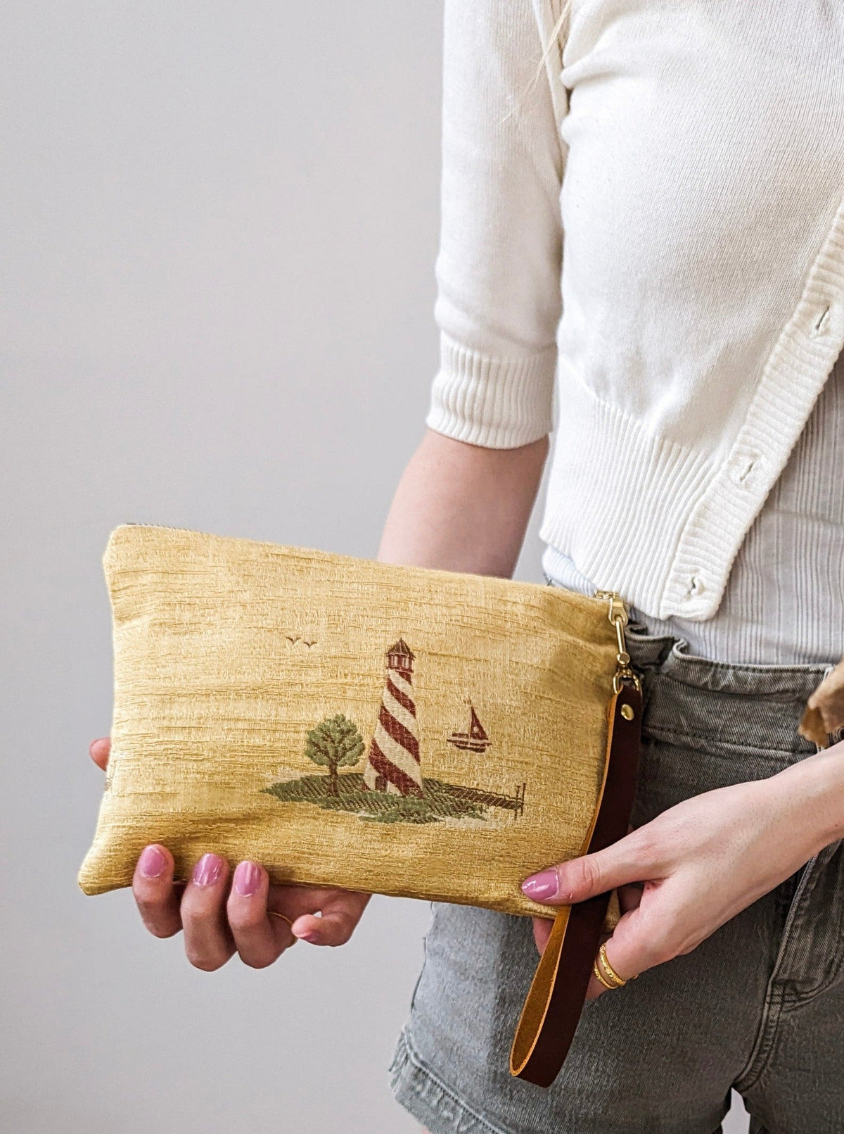 Linen wristlet with embroidered lighthouse and sailboat, zipper, and leather wrist strap