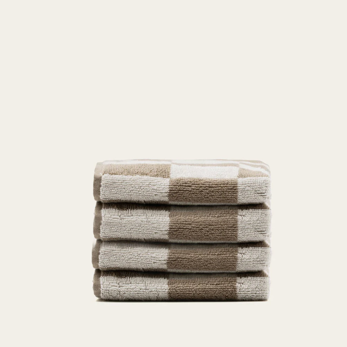 Folded tan and ecru cotton towels with checkered grid accents, neat stack