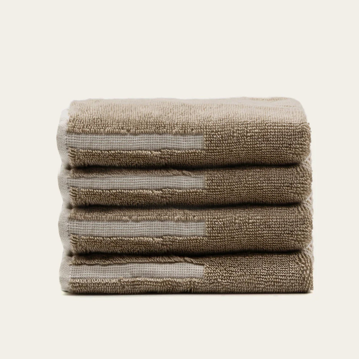 Cotton towel stack in tan with ecru stripe details, folded and layered