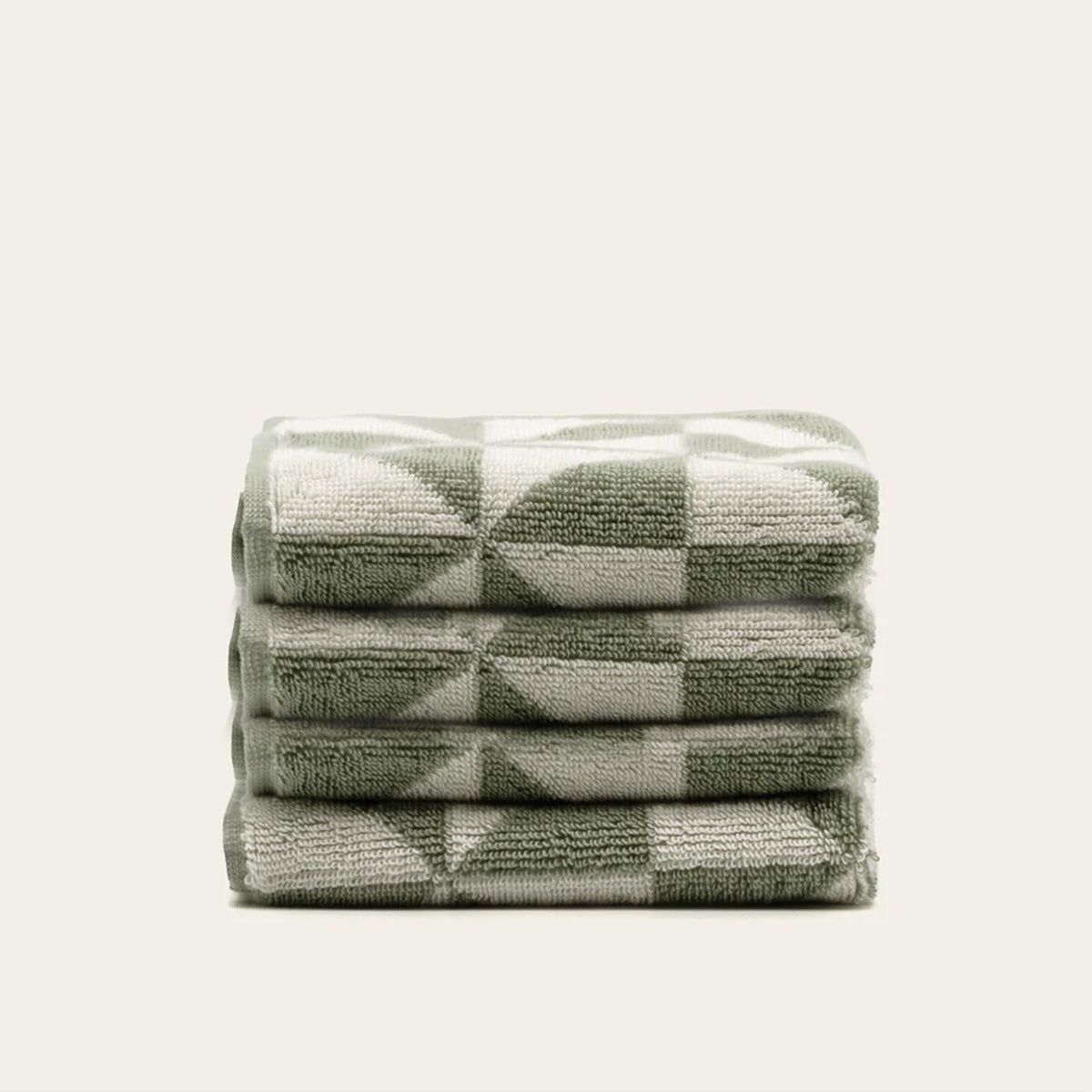 Stacked geometric cotton towels in sage green and ecru with triangular pattern blocks.