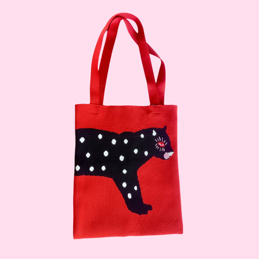 Red knit tote bag with black polka-dot cat graphic and long matching handles.