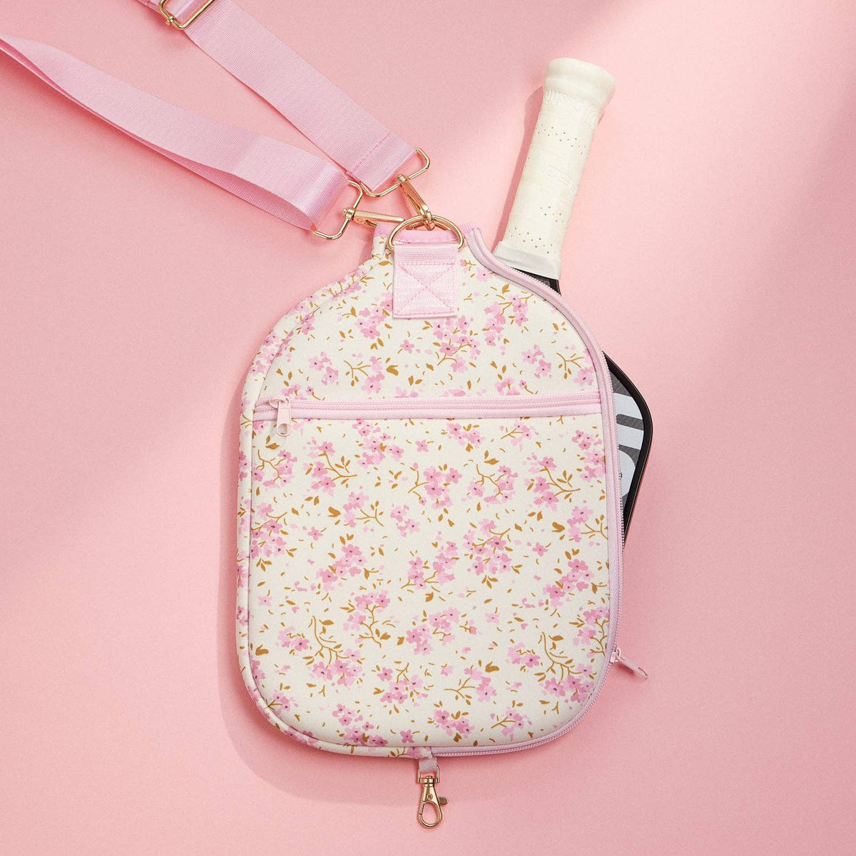 Floral neoprene pickleball paddle bag shown with paddle handle inside and front zip pocket