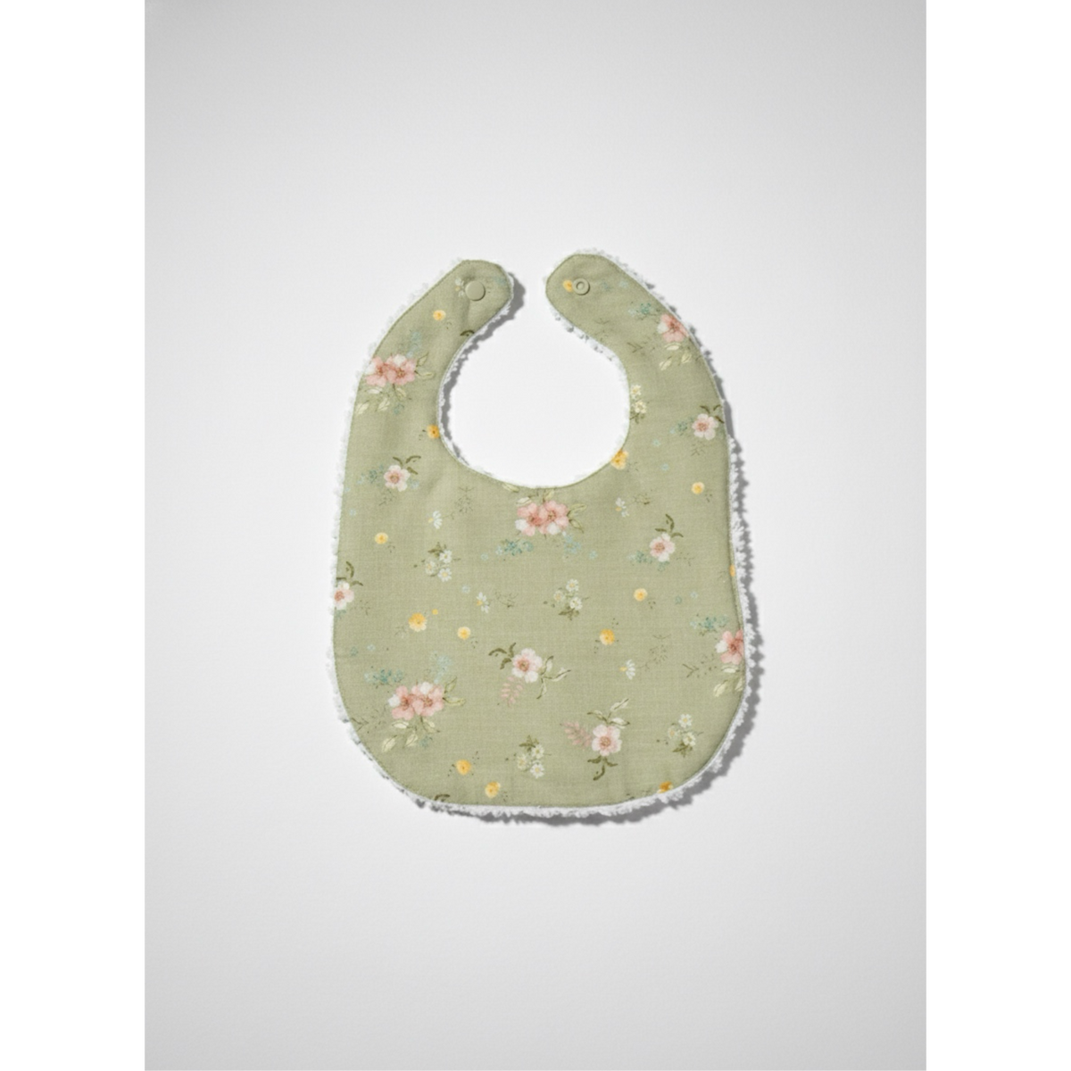 Infant linen bib with sage floral print, rounded neck opening, stitched edge trim