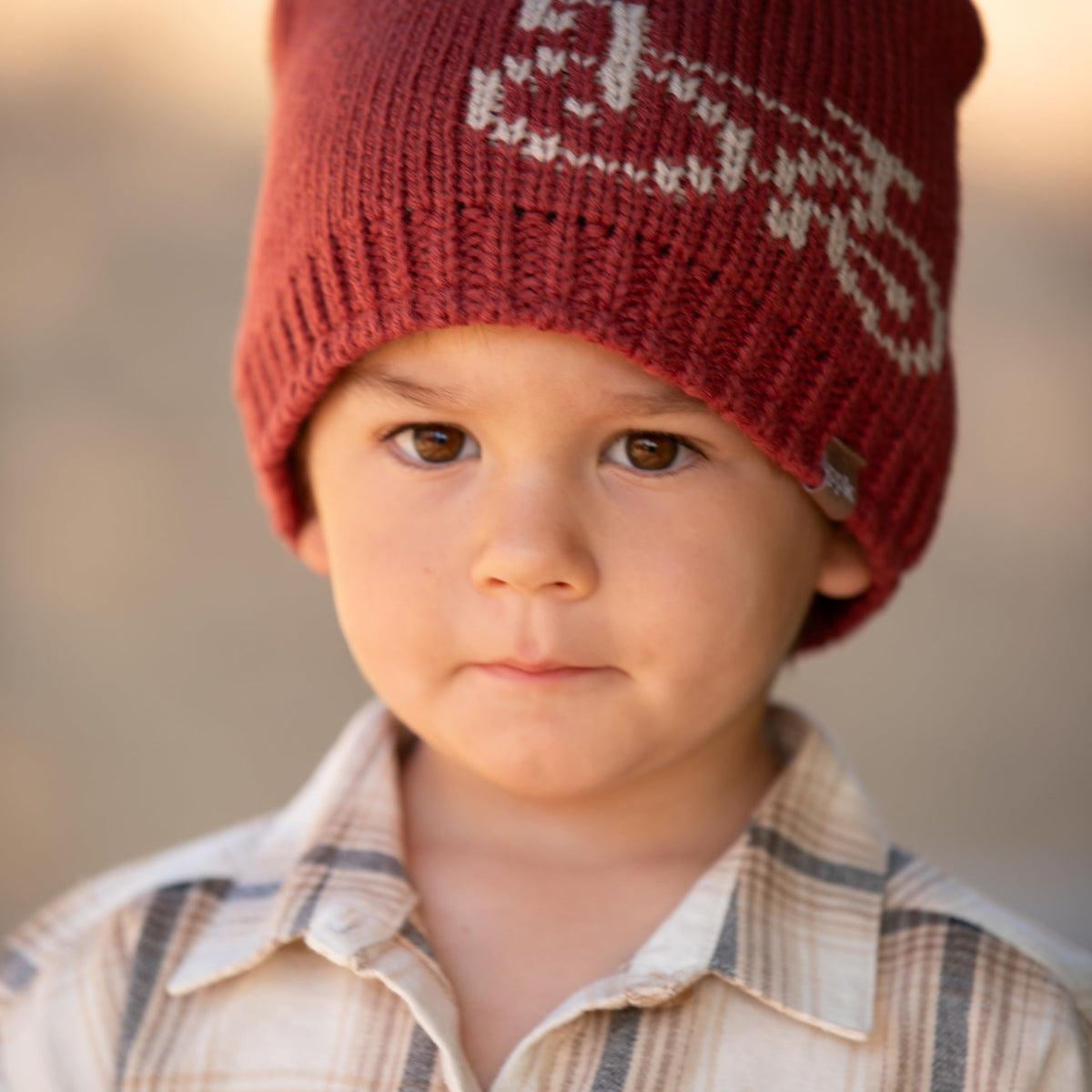 Red knitted beanie with a white graphic, worn by a child