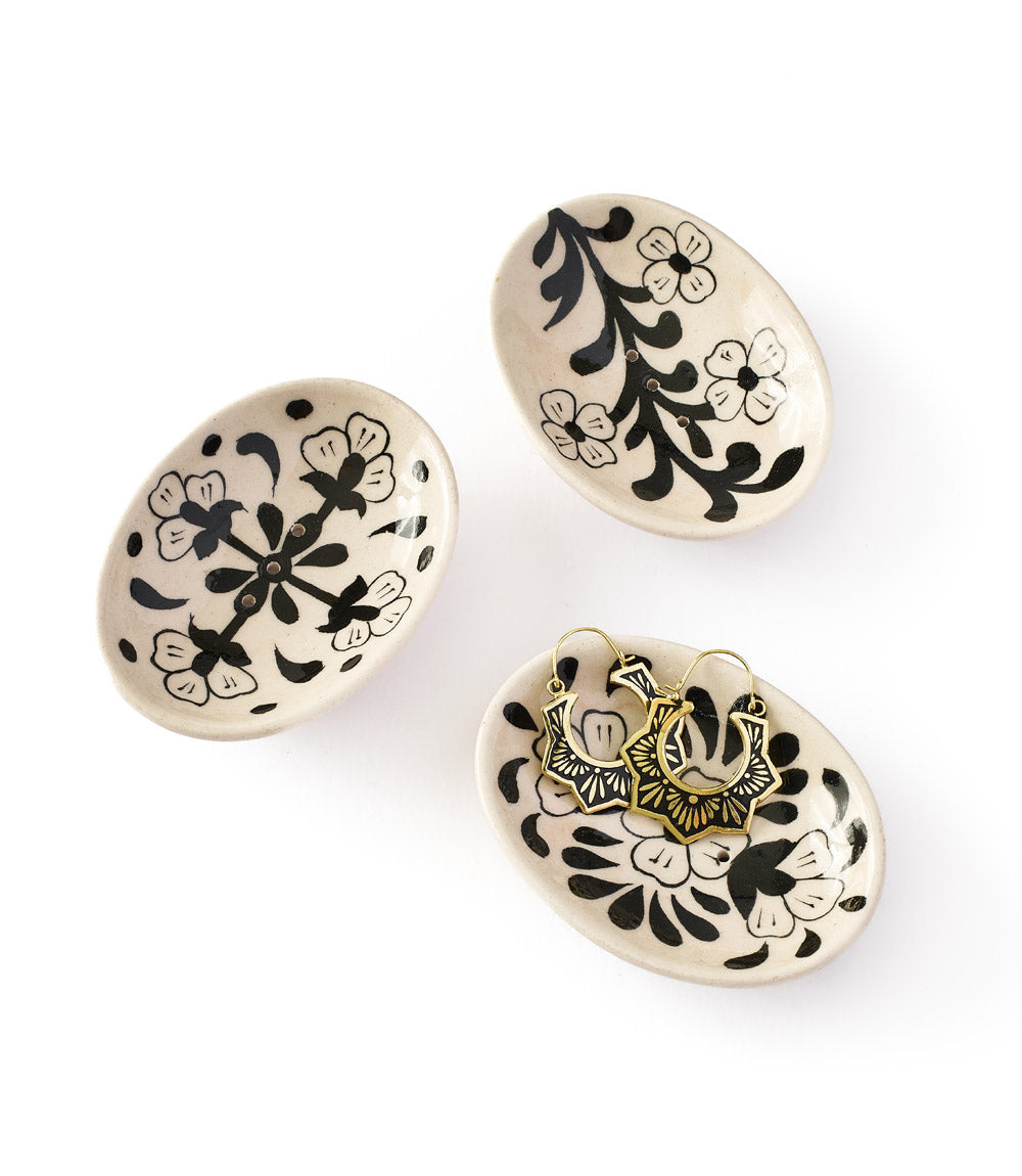 Three cream ceramic trinket dishes with black floral art and gold hoop earring pairs