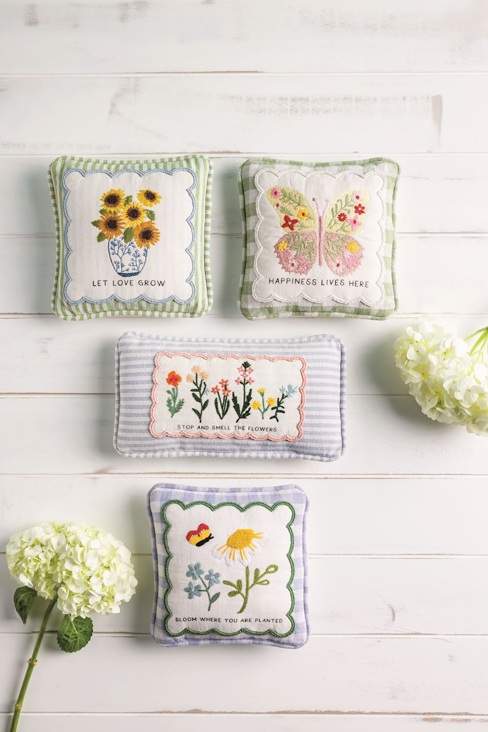 Three embroidered mini accent pillows with floral embroidery and motivational phrases