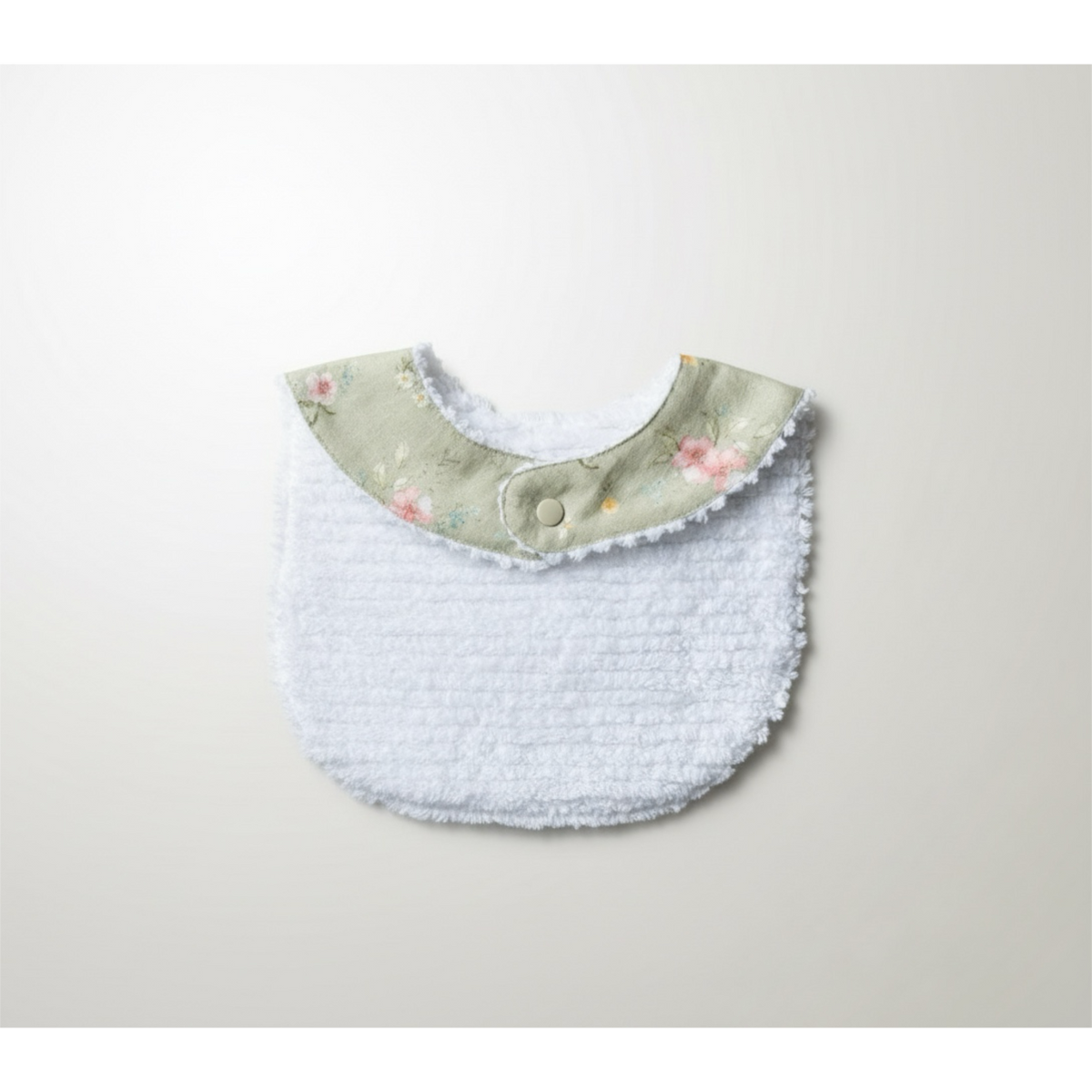White terry baby bib with light blue body and floral green collar with snap button.