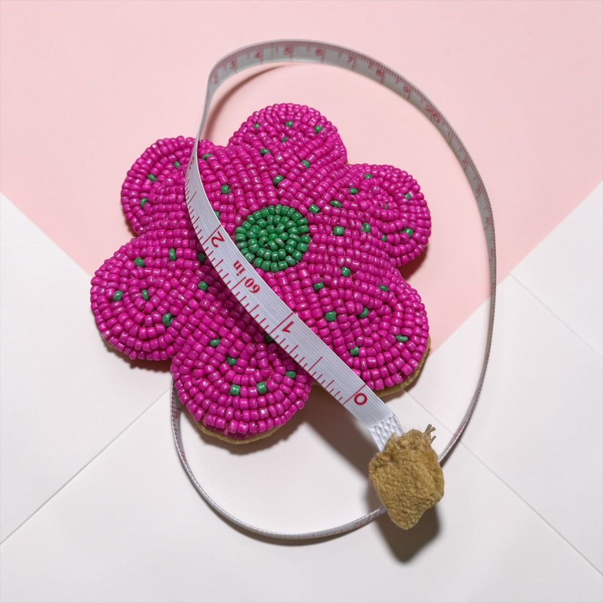 Glass beaded flower tape measure with fuchsia flower and measuring tape wrapped around it