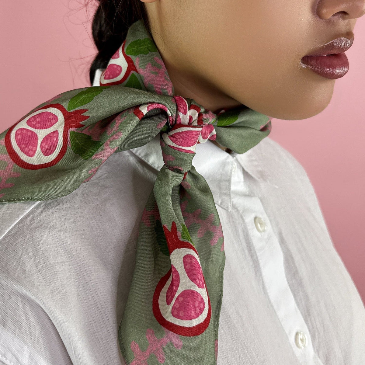 Green patterned bandana tied at the neck with pink pomegranate fruit motifs
