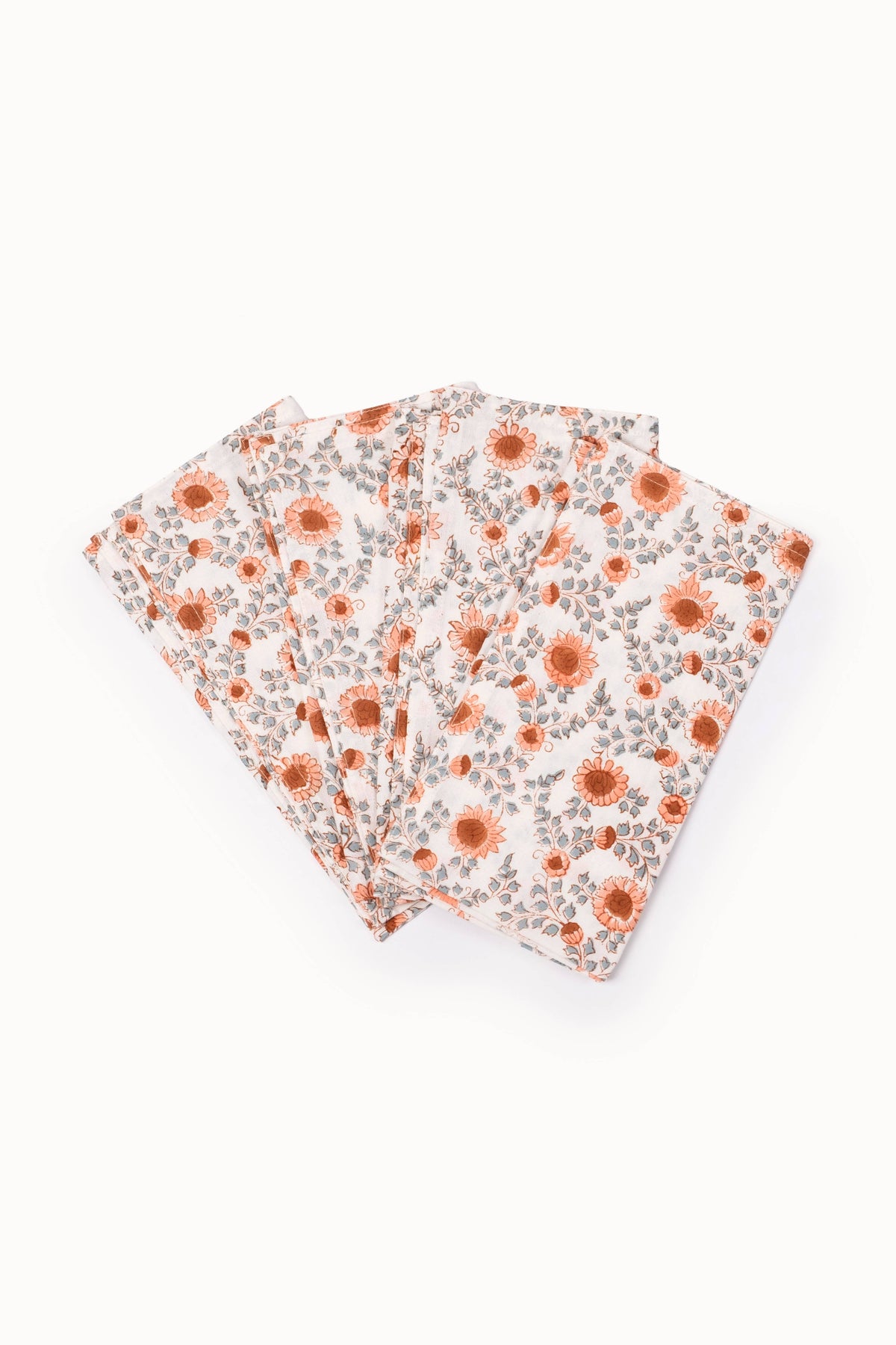 Floral block-printed napkins, folded; terracotta blooms on a white background