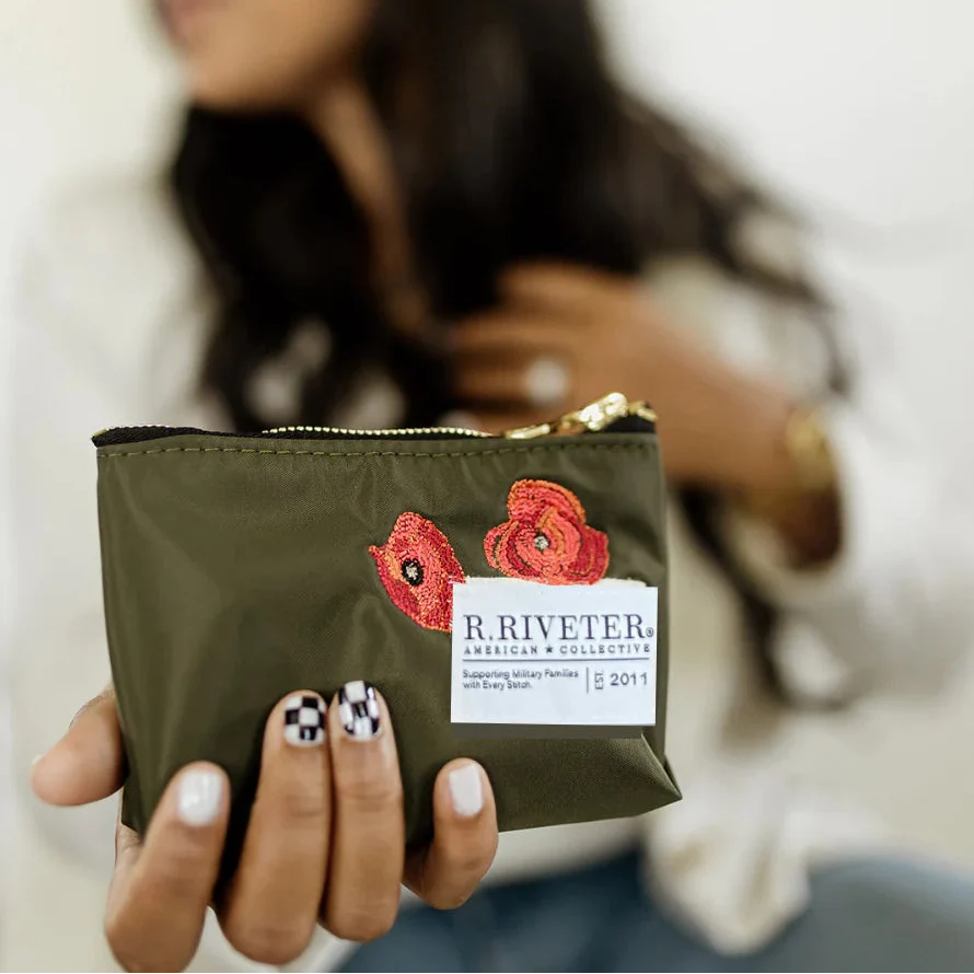 Lucy mini zipper pouch, fatigue green with floral patch and gold zipper, held in hand