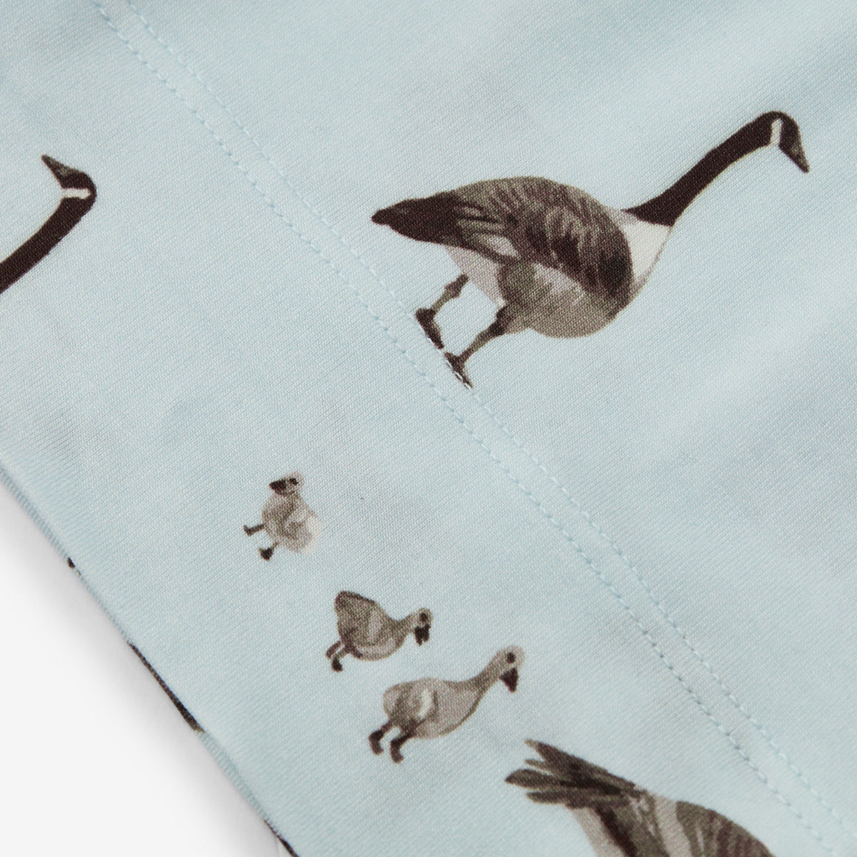 Light blue beanie hat fabric with stitched animal print and visible seam