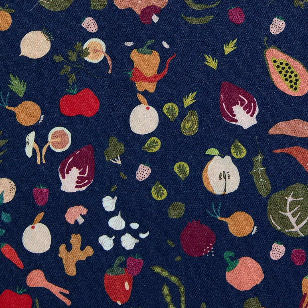 Blue fabric with colorful fruit-and-leaf print, close-up of cotton apron pattern