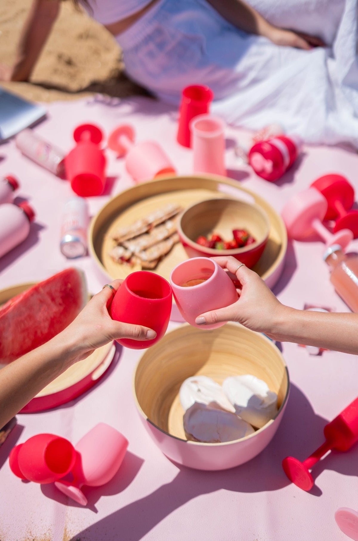 Silicone unbreakable tulip glasses in red and blush pink, held at a picnic table