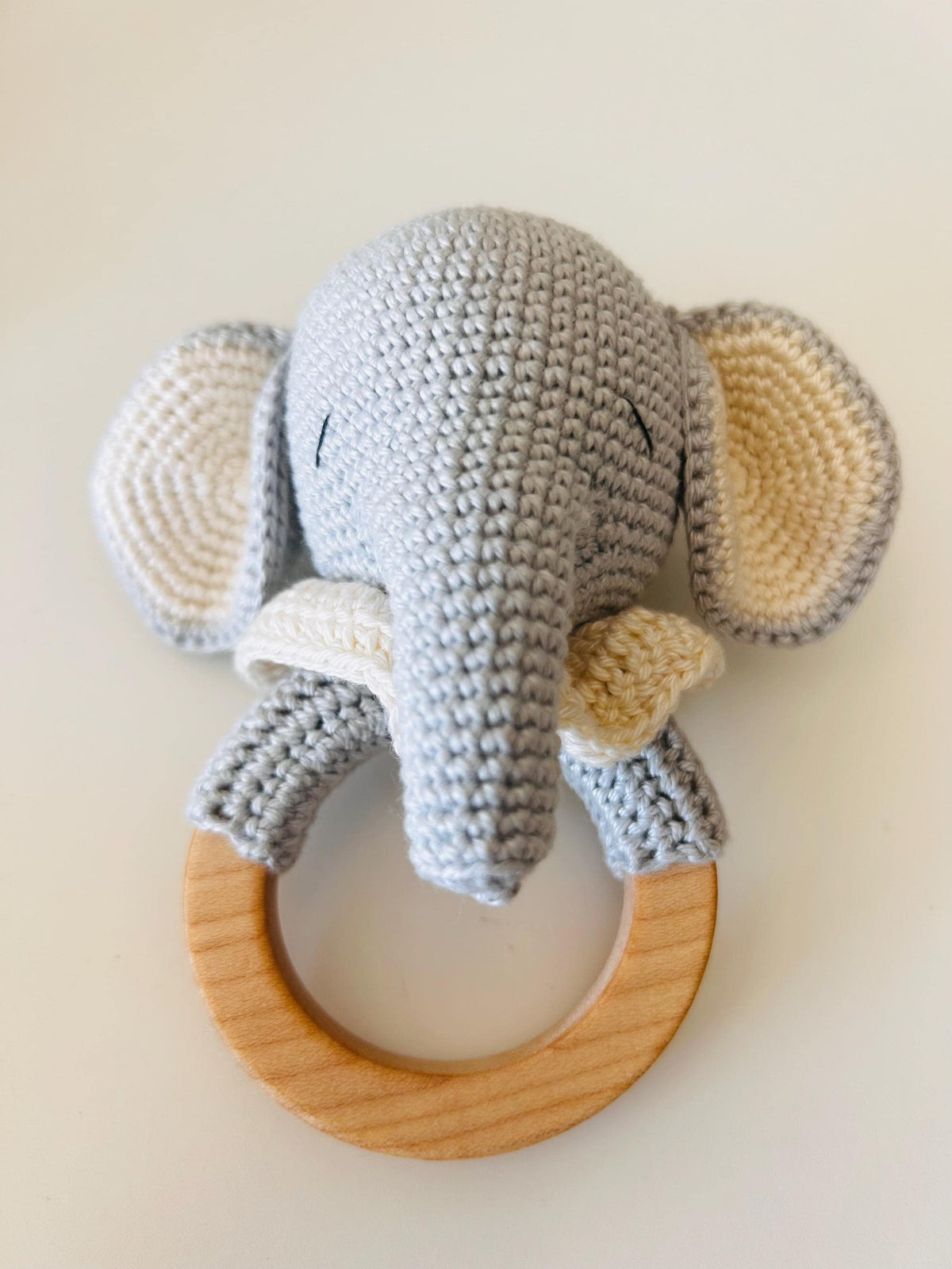 Gray knit elephant baby rattle with light wood teether ring and textured ears