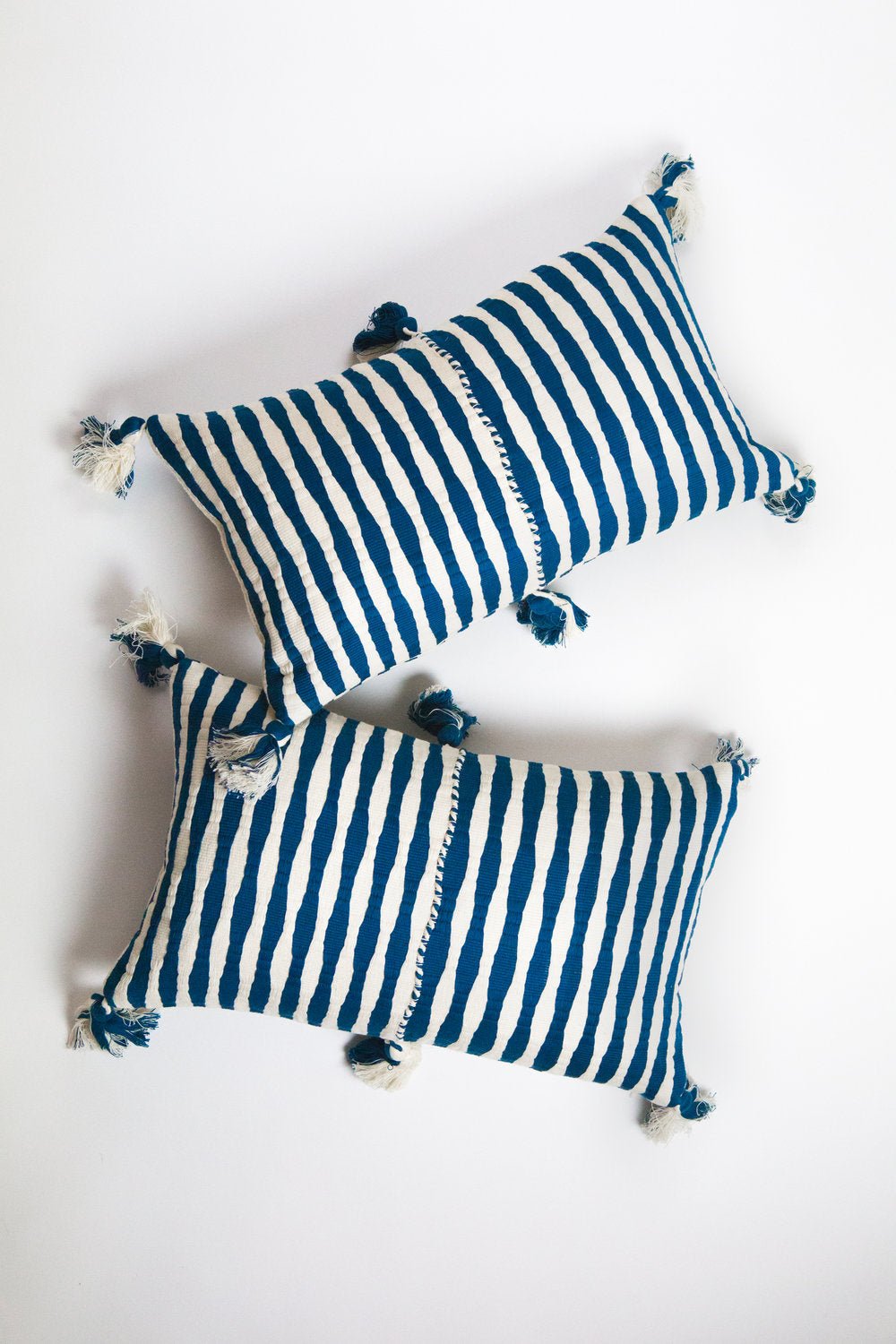 Striped throw pillow with dark teal and white stripes and tassel corners